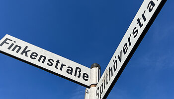 Straßenschild Finkenstraße und Spithöverstraße vor blauem Himmel.