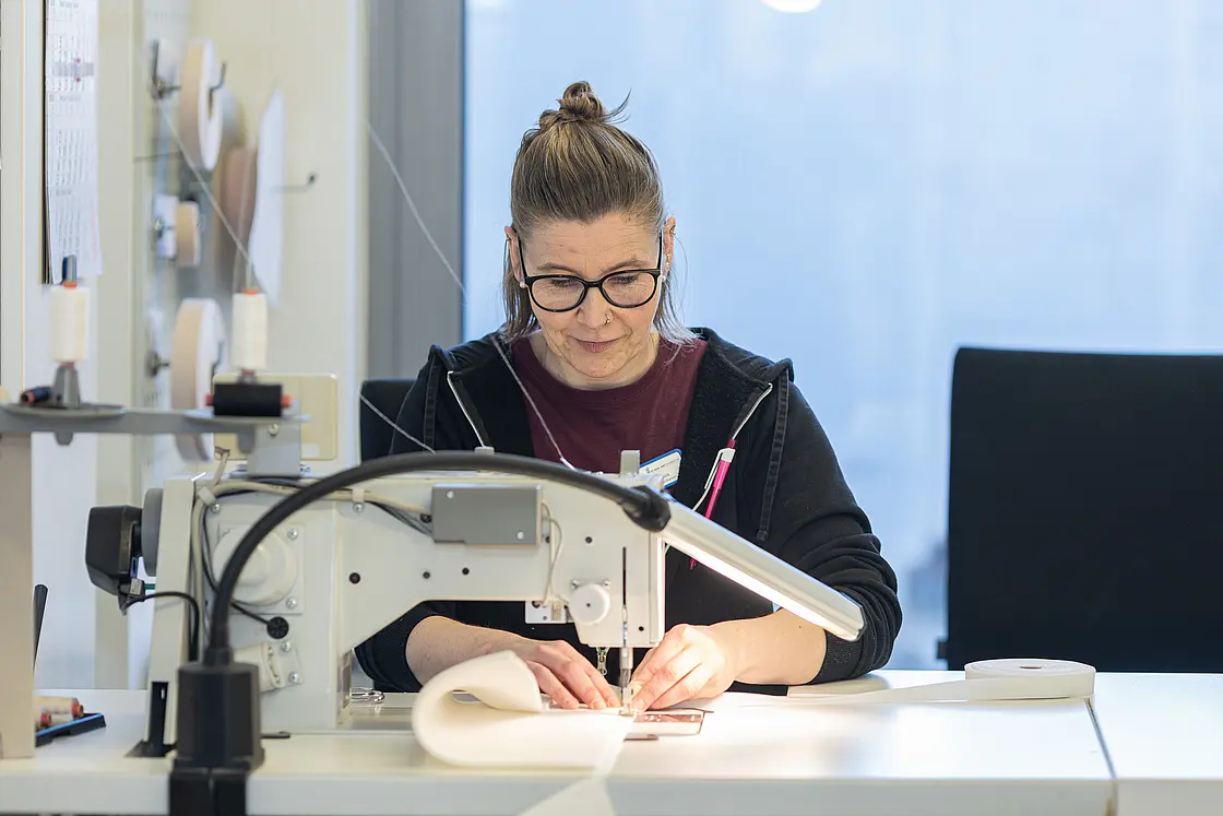 Mitarbeiterin näht ein orthopädietechnisches Bauteil an einer Industrienähmaschine.