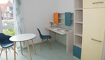 Modernes Apartment mit Bett, Sitzbereich, Schreibtisch und großem Fenster.