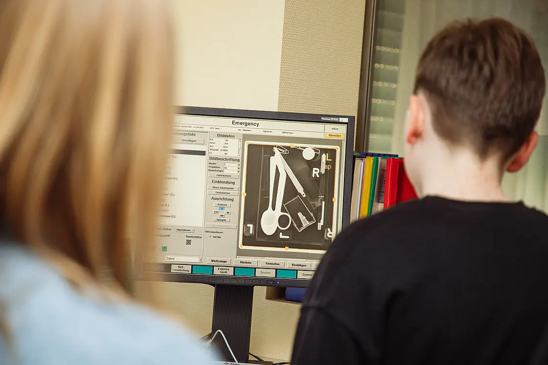 Zwei Jugendliche betrachten gemeinsam eine medizinische Aufnahme am Computerbildschirm.