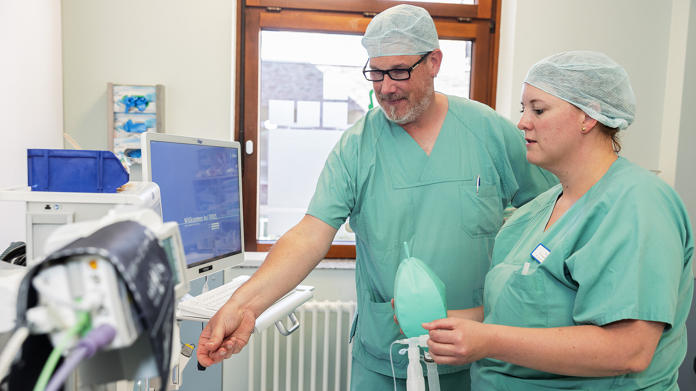 Zwei Intensivpfleger:innen nutzen einen telemedizinischen Monitor zur gemeinsamen intensivmedizinischen Fallbesprechung.