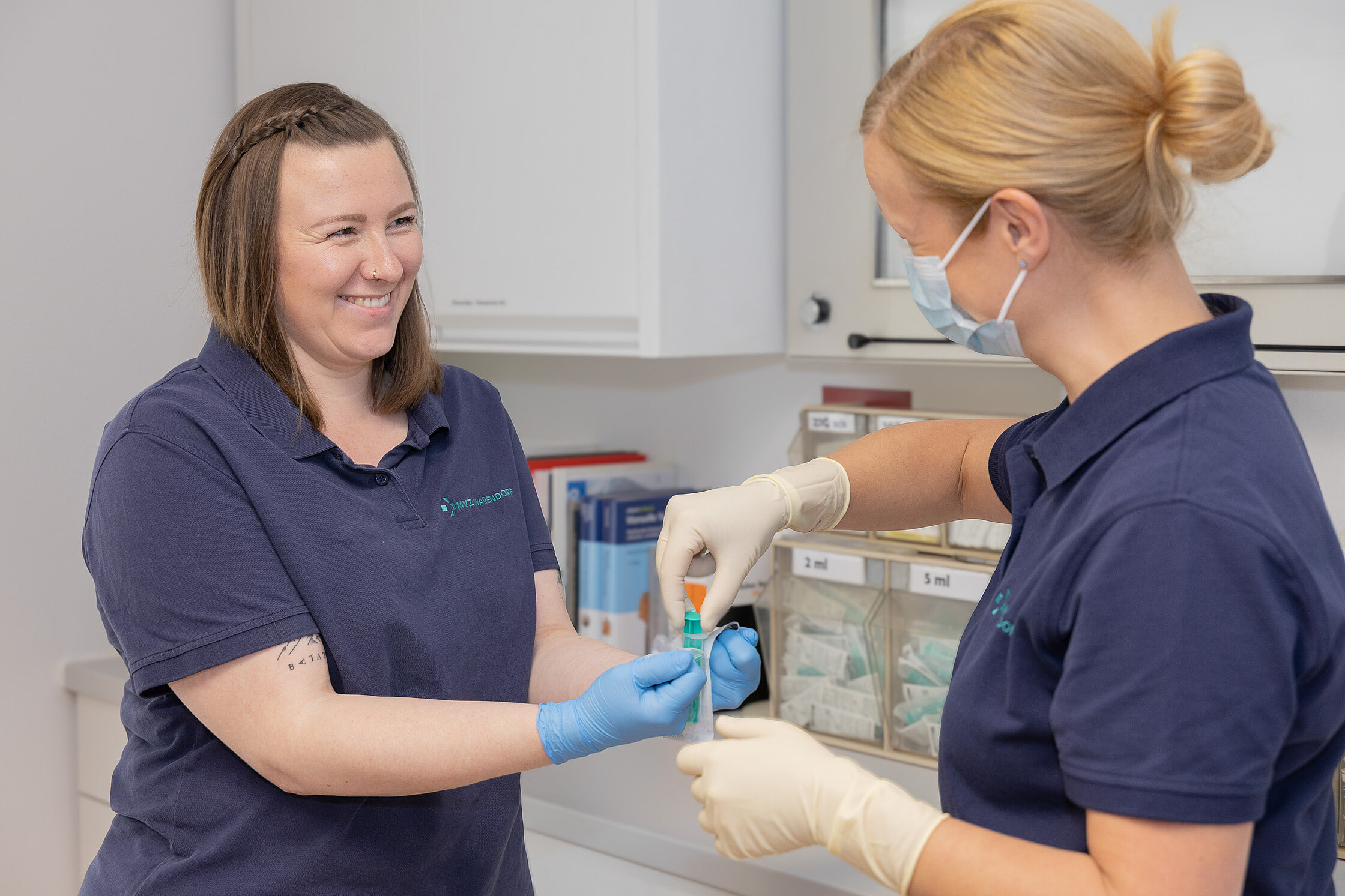 Zwei Mitarbeiterinnen des MVZ Warendorf bereiten im Praxisraum gemeinsam eine Blutprobe vor; eine trägt Handschuhe und hält ein Probenröhrchen.