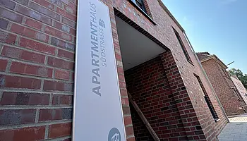 Eingangsbereich des Apartmenthauses Südstraße mit überdachtem Zugang und Backsteinfassade.