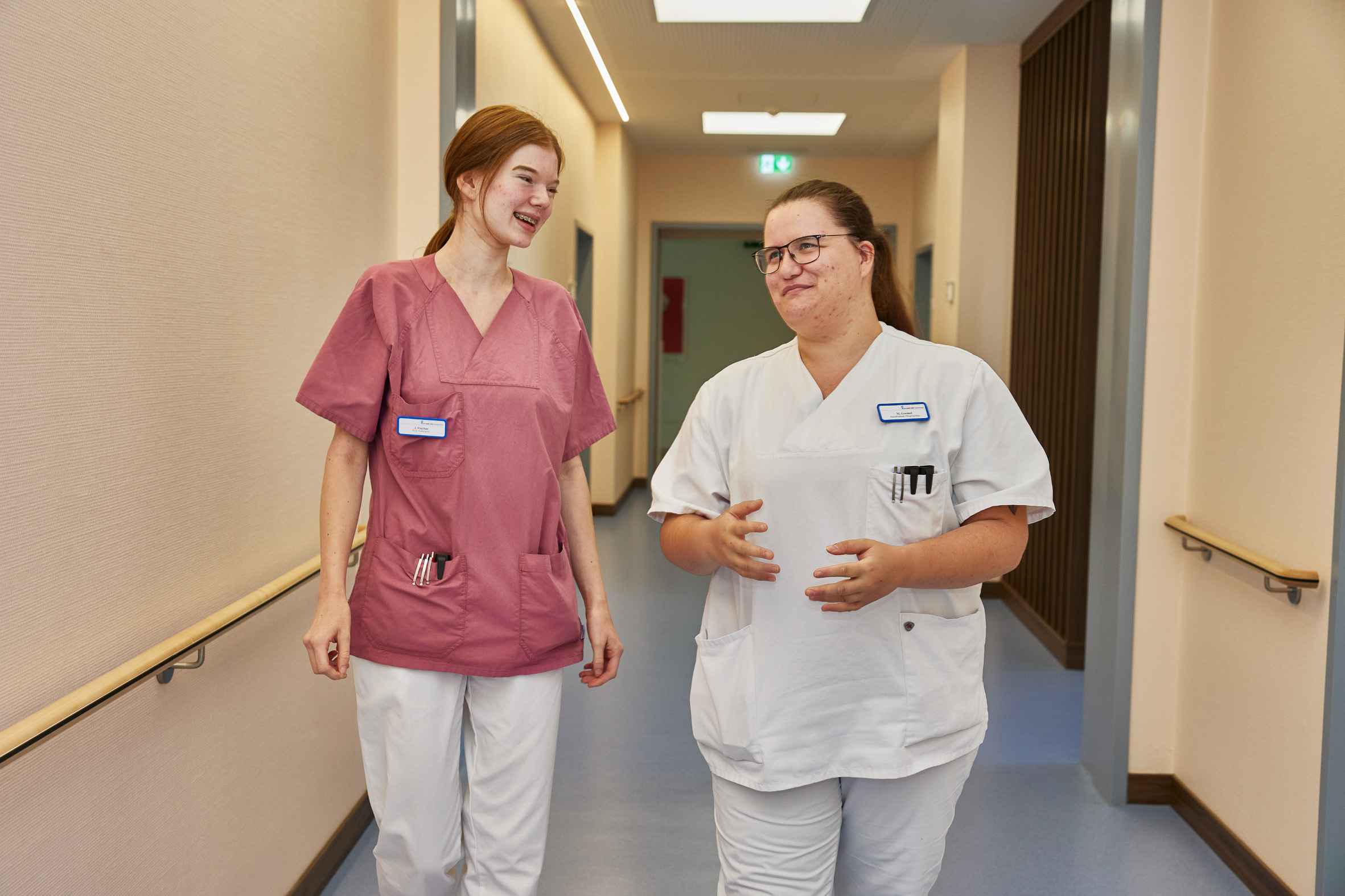 Zwei Pflegerinnen laufen über den Flur einer Station